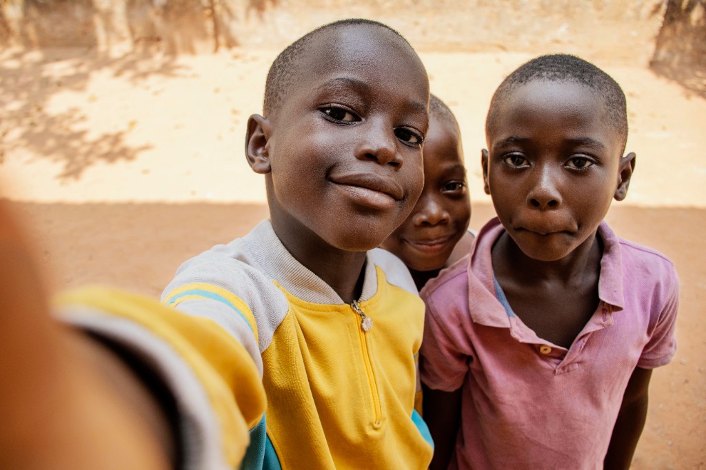 Three young boys smiling together, helping each other